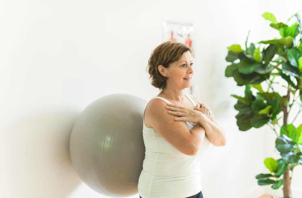 An older adult woman doing wall squats with a fit ball
