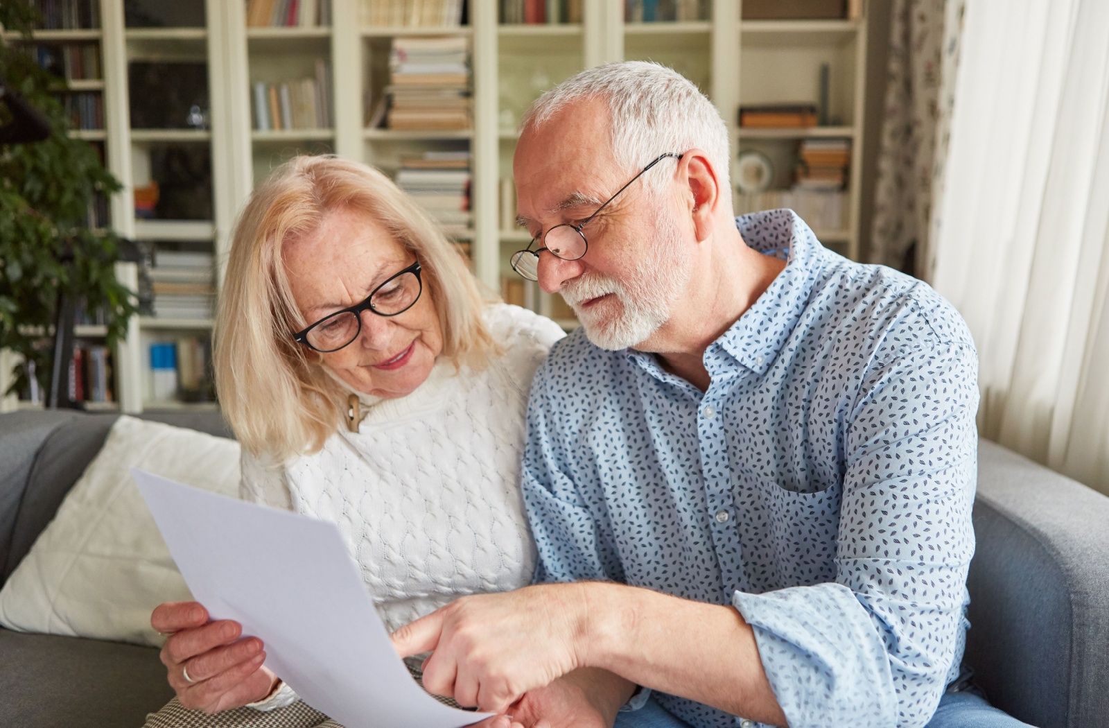 An older adult and his spouse looking at power of attorney documents while sitting on a couch.