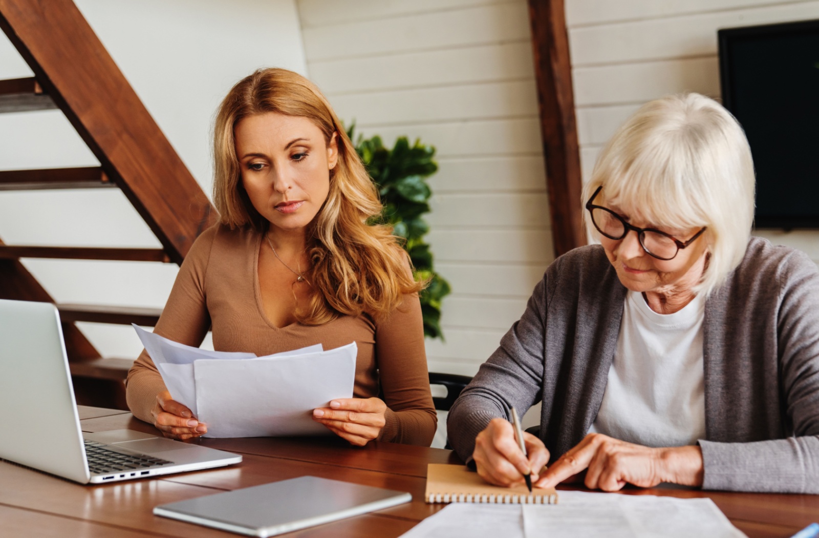 A legal expert helps an older adult understand power of attorney requirements and documents while sitting at a table.
