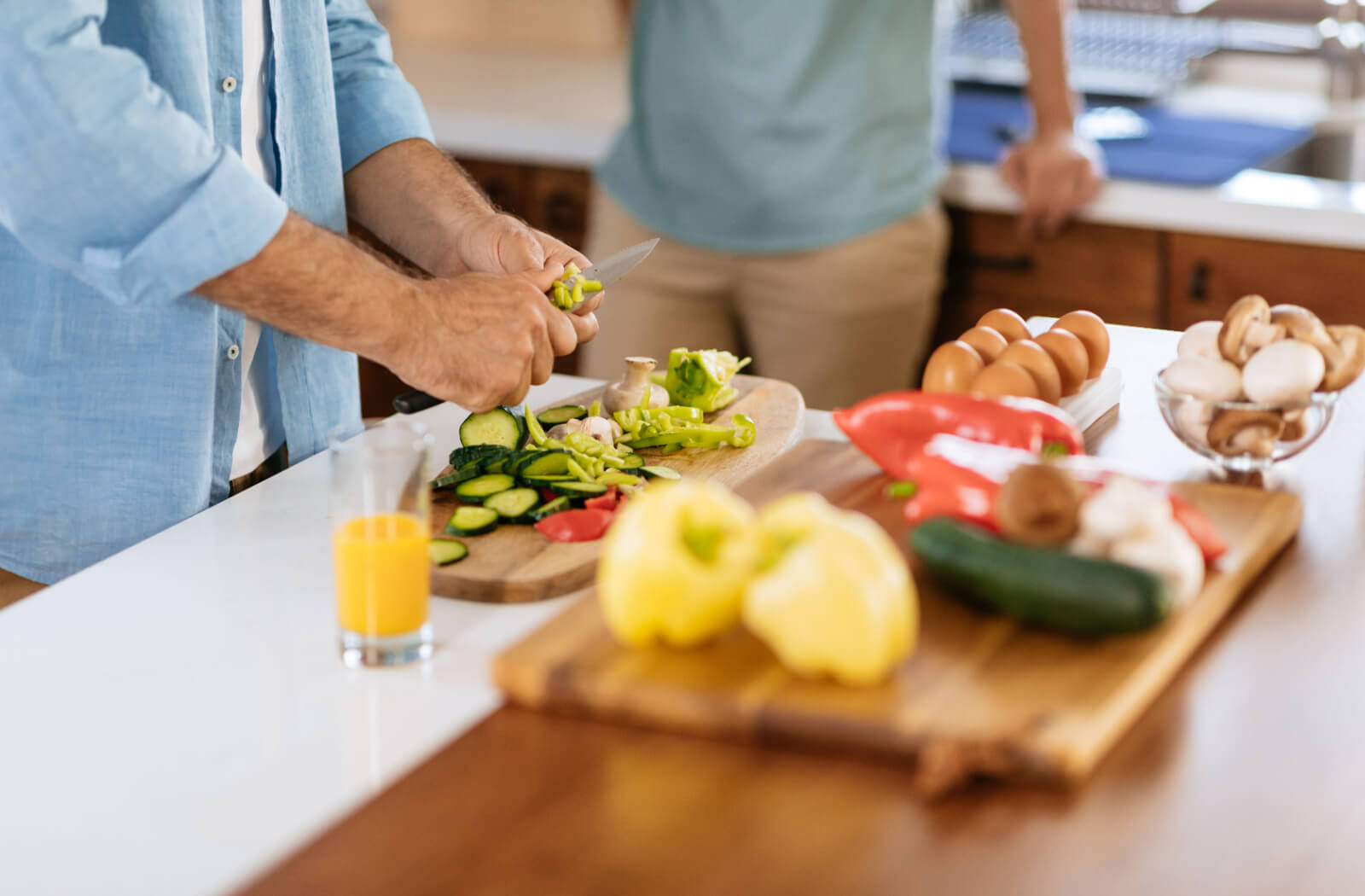 A close-up of an older adult cutting vegetables and preparing a meal in their kitchenette.