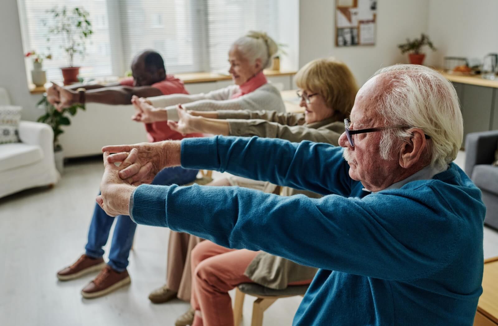 A group of seniors performing gentle chair exercises together.