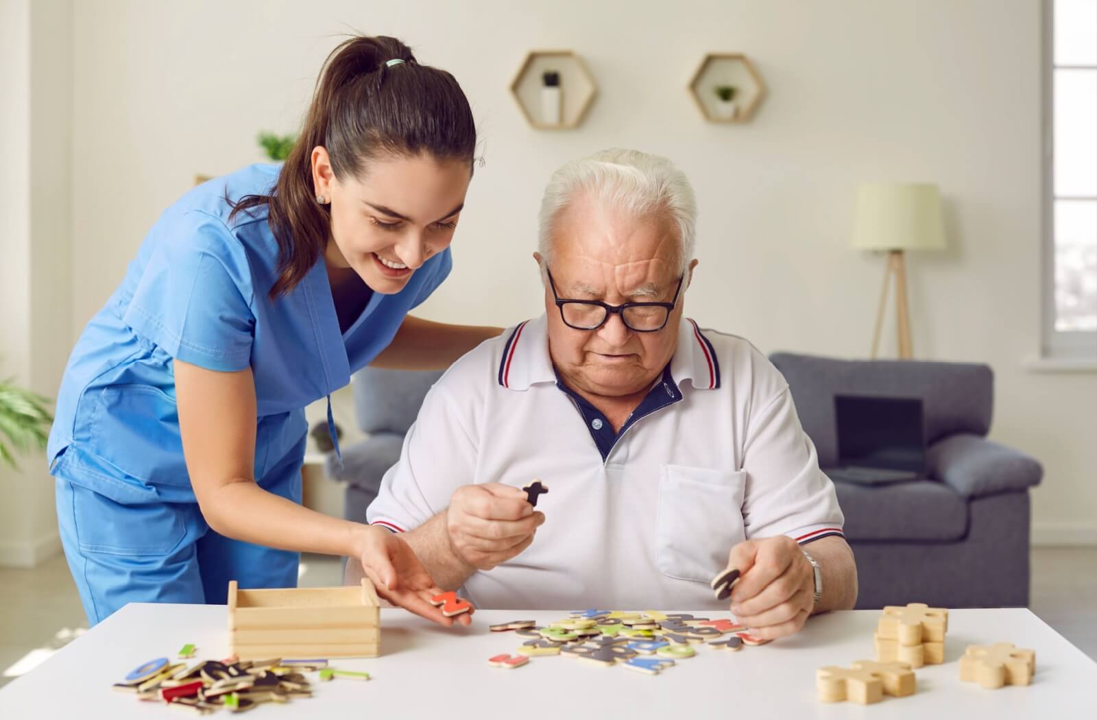 A caregiver helps a senior with a cognitively engaging puzzle in a memory care community.