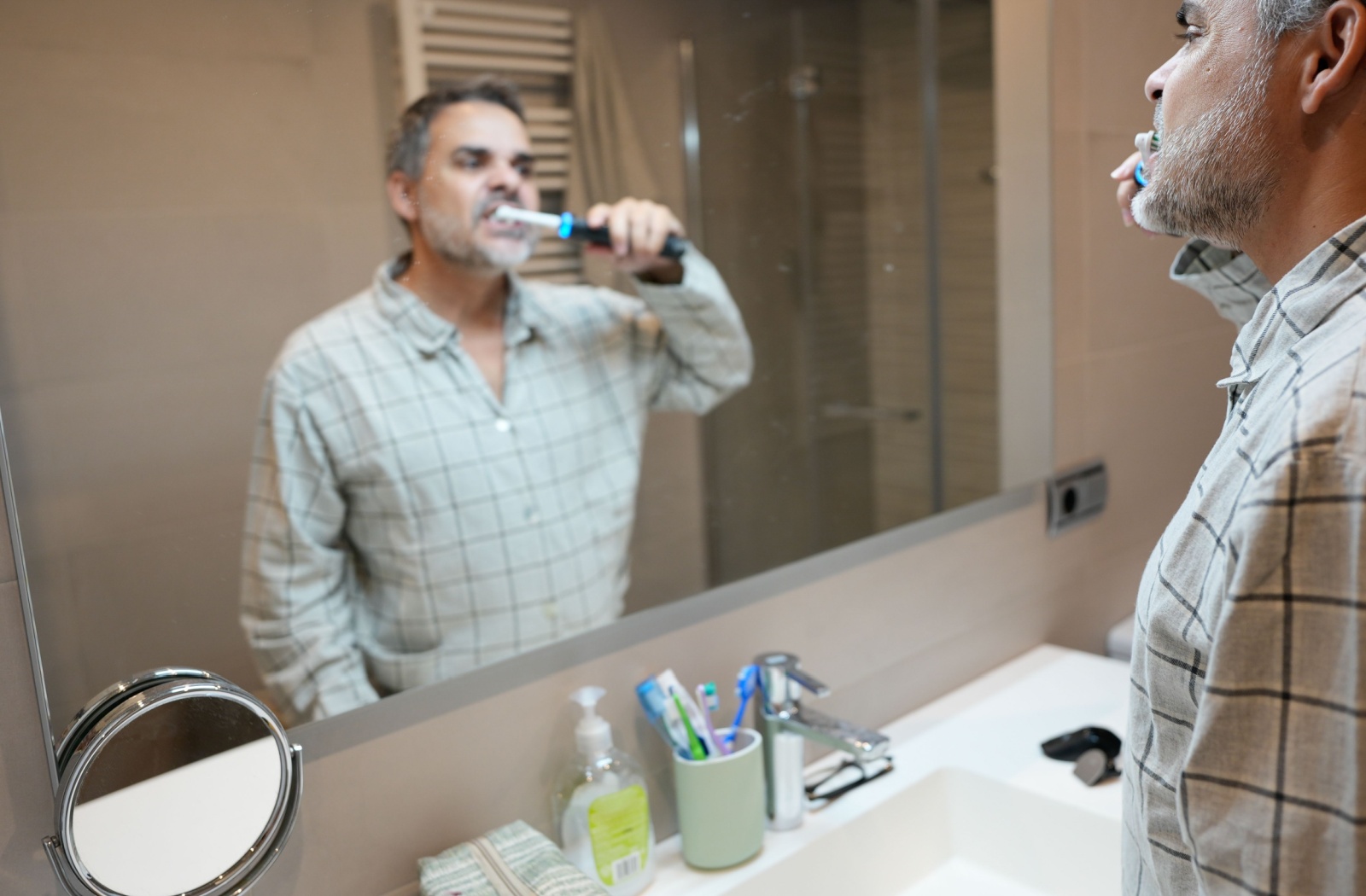An older adult brushes their teeth with an electric toothbrush.