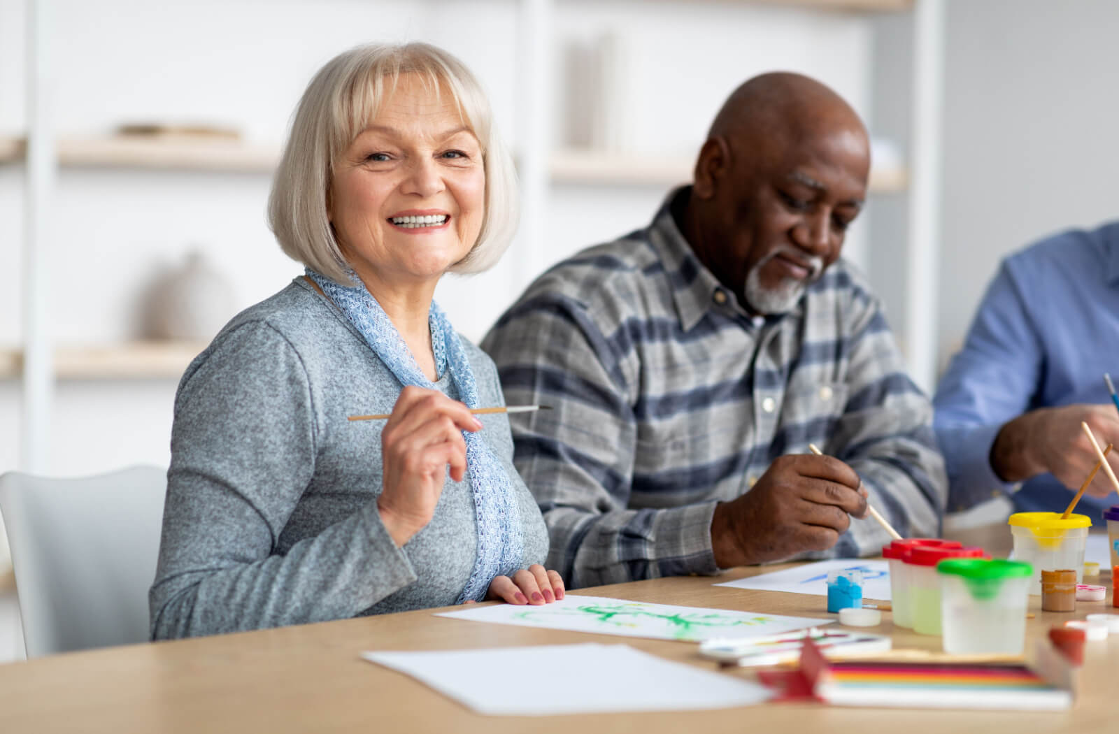 An older adult smiling during a painting workshop in senior living.