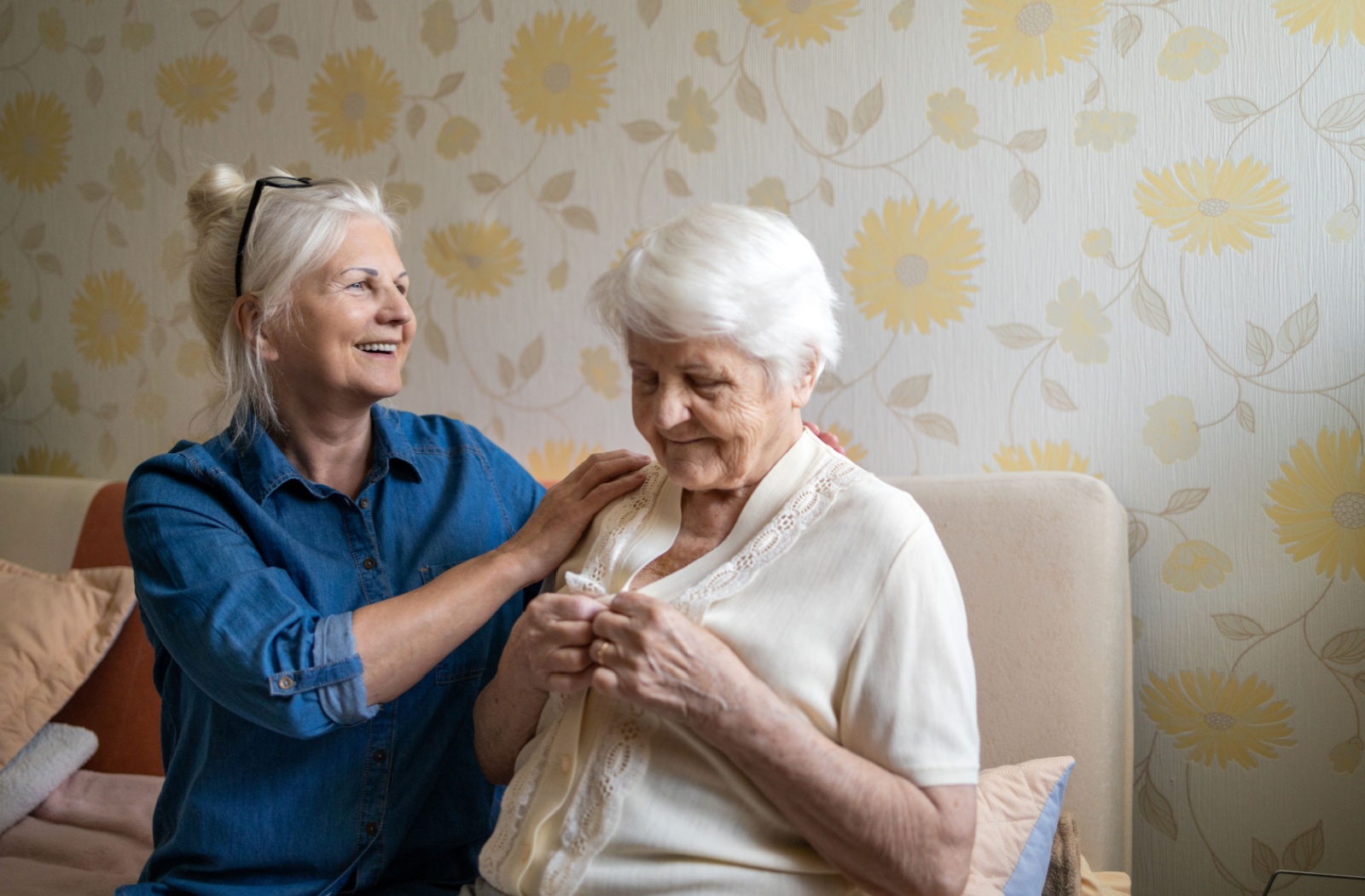 An adult helps their older parent with dementia get dressed in their bed to account for changes they’re experiencing